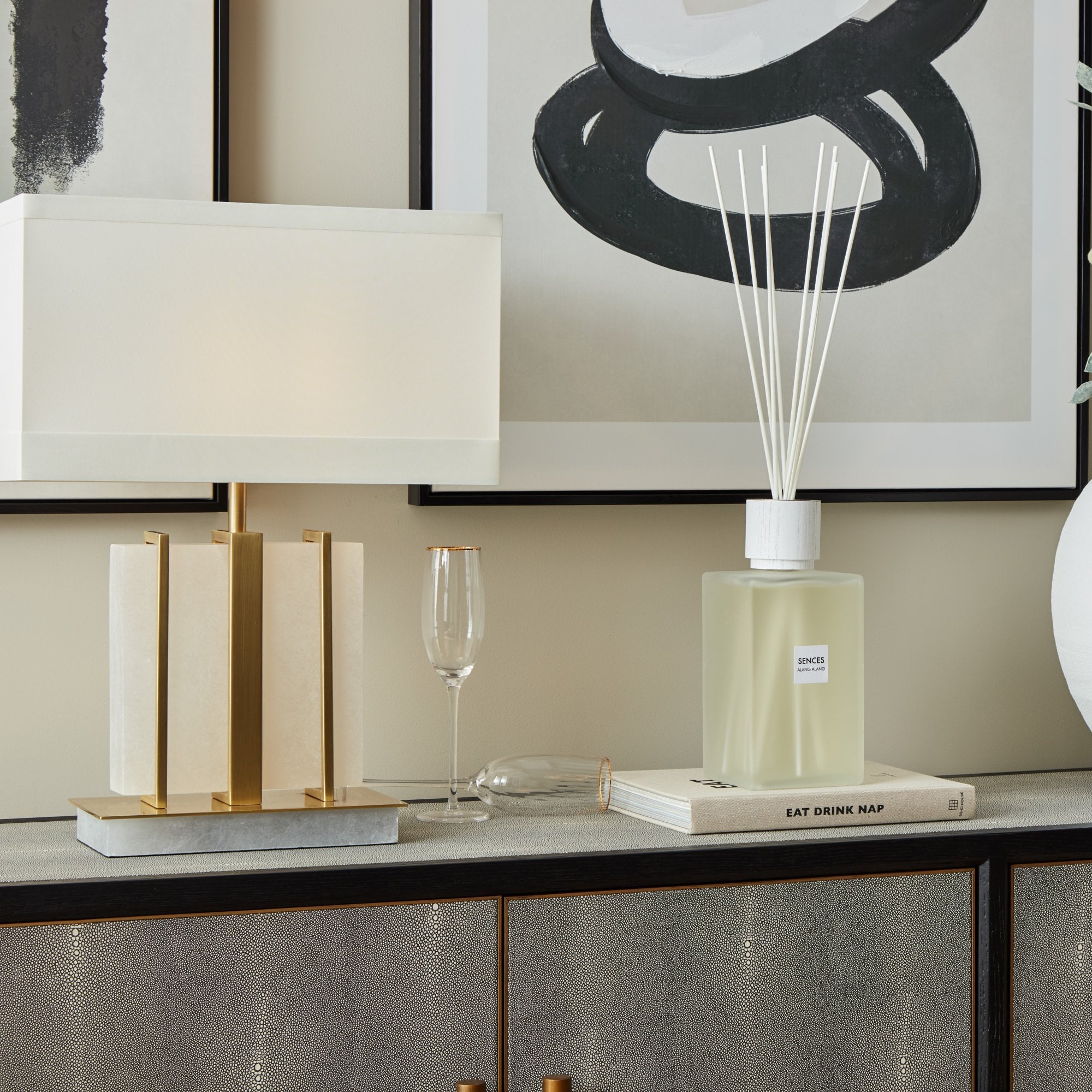 Kelcie Table Lamp and Decorative items on a shelf including a lamp, books, a glass, and a diffuser.