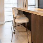 Xenia Beige Leopard Counter Stool (Set of 2) by Richmond Interiors with bronze metal detail under a kitchen island counter.